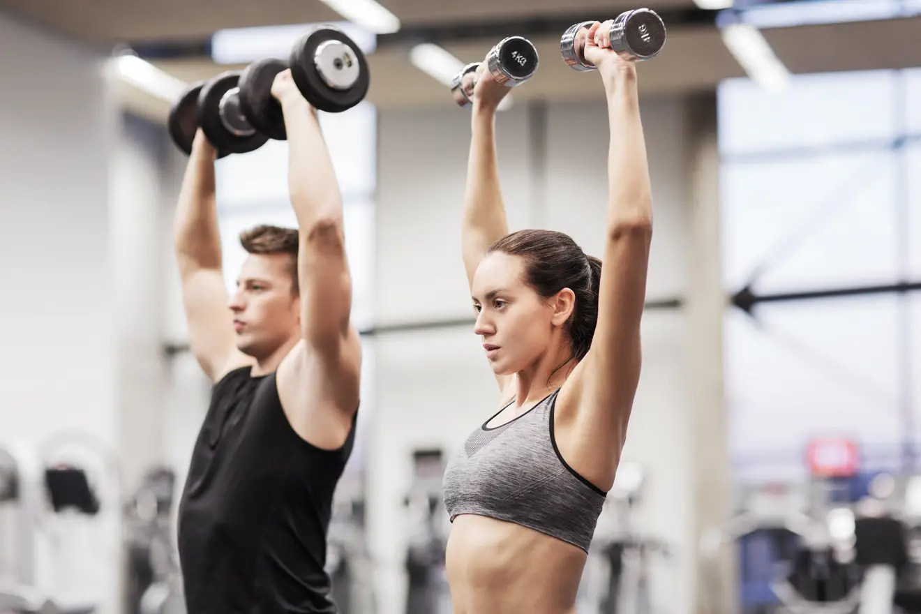 Man and woman doing dumbbell overhead press