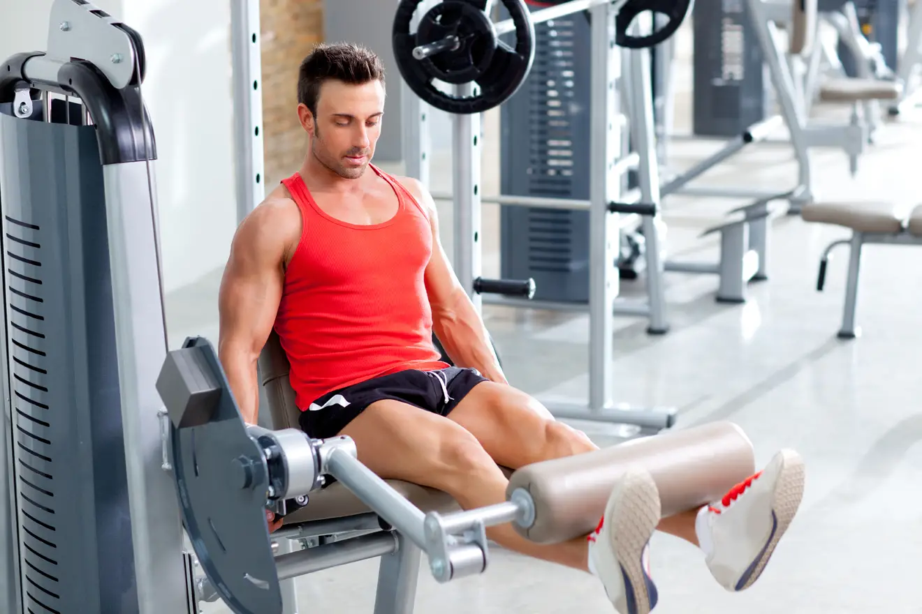 Man doing leg extension exercise in gym