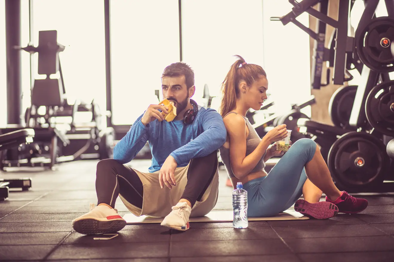 Man and woman eating in gym