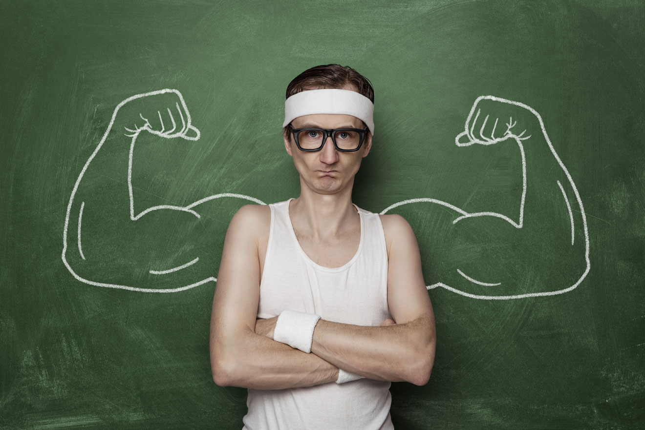 Skinny man in front of black board with muscular arms drawn behind him