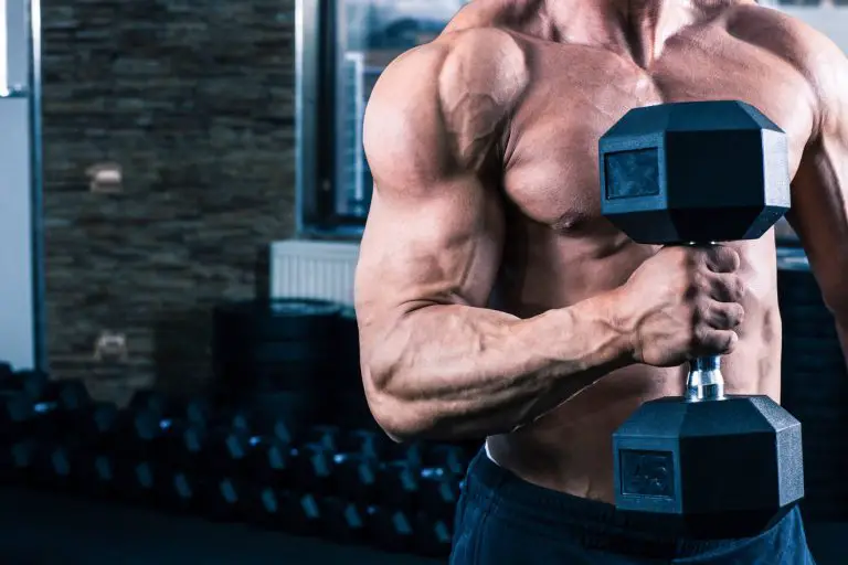 closeup of a man with large biceps and deltoid muscles lifting a heavy dumbell