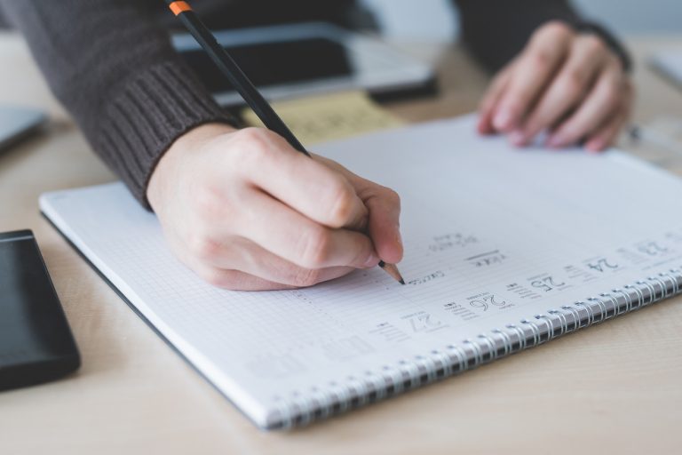 close up on male hand writing a schedule on a notepad