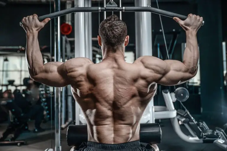 shirtless man in gym doing lat pulldown exercise