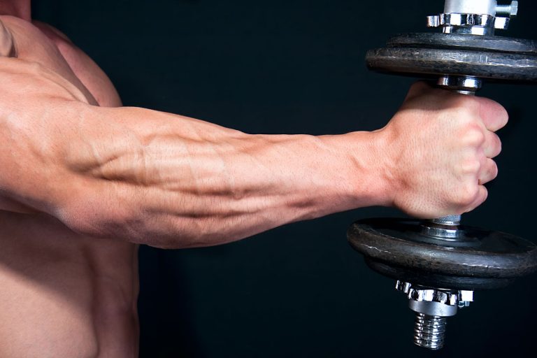 Muscular man holding one dumbbell out in front of him