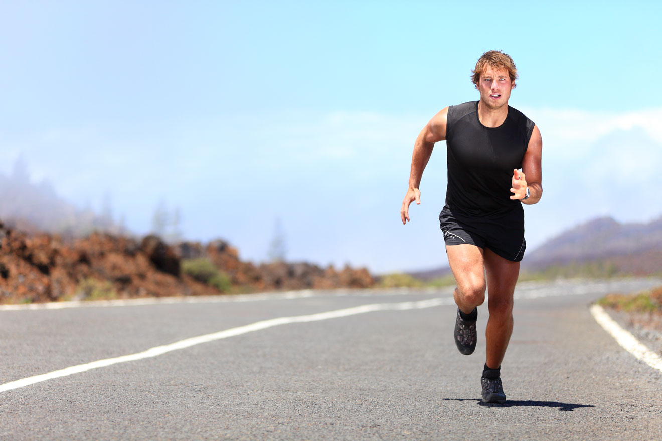 Man running in the road on a sunny day wearing shorts