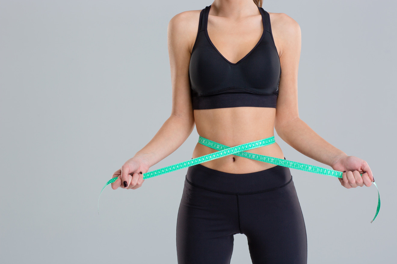 athletic woman with measuring tape around waist