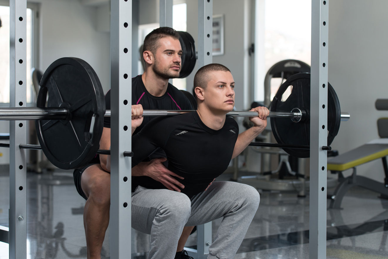 personal trainer spotting client on Smith machine