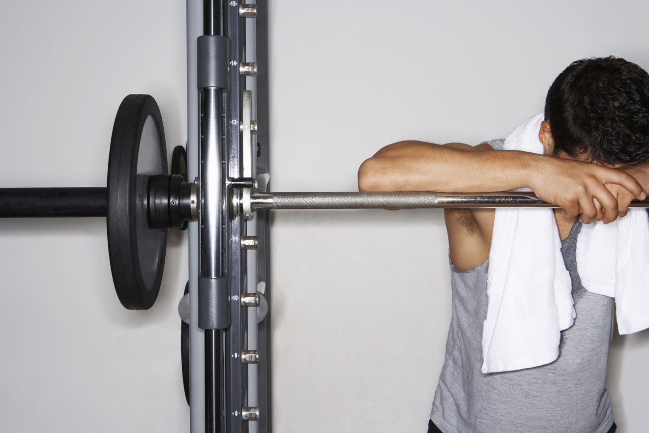 Tired man leaning against Smith machine