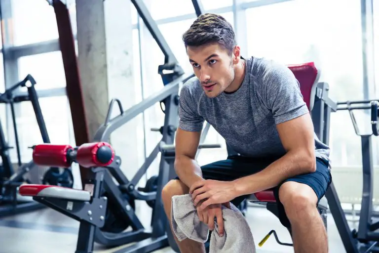 unmotivated gym man sitting on gym equipment