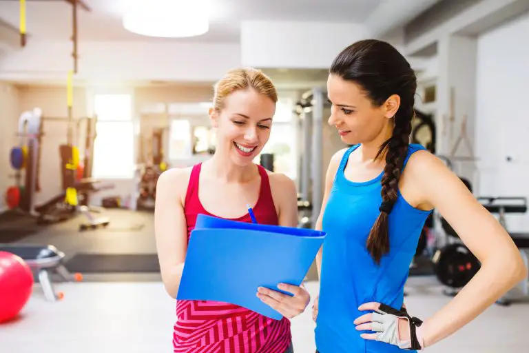 woman in a gym consulting with personal trainer exercise plan