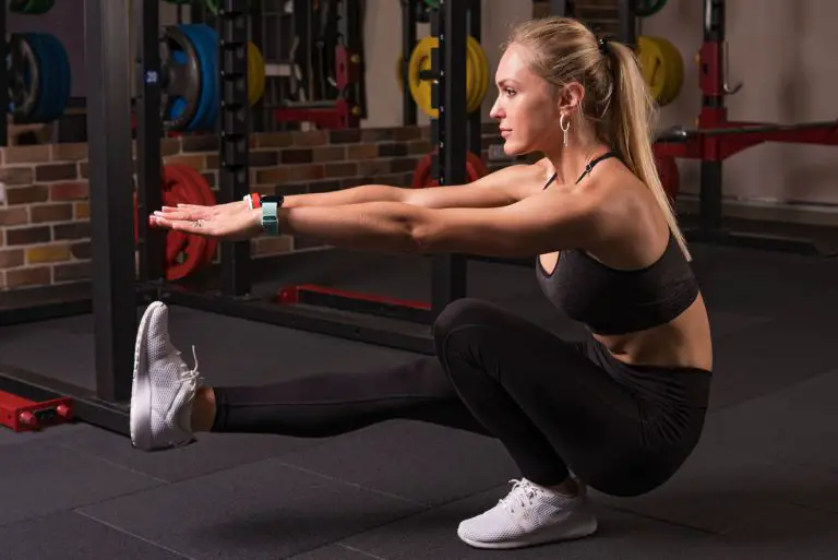 Young woman doing one-leg bodyweight squat in gym