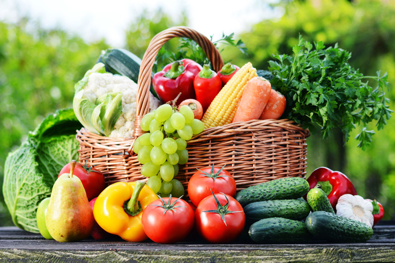 A basket of colorful fruits and vegetables on a wooden table