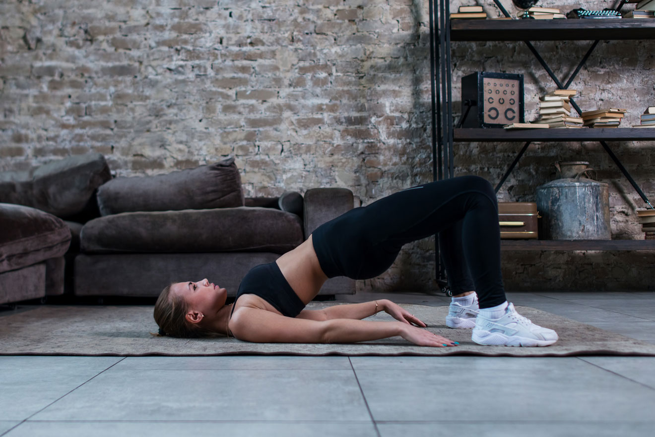 Young woman at home doing glute bridge exercise