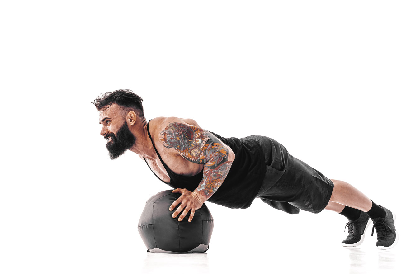 Man doing front plank on medicine ball outside