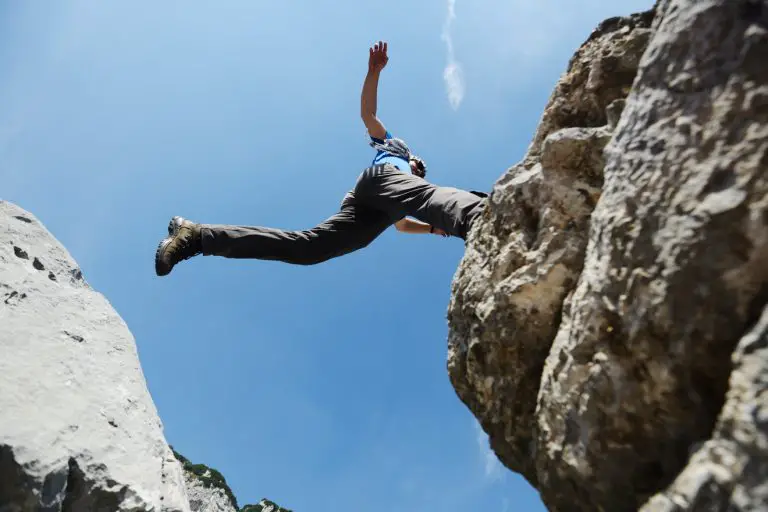 hiking man jumping over the mountains