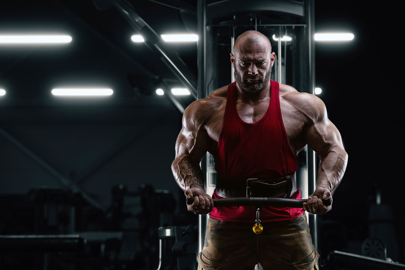 Muscular man in gym doing cable biceps curl