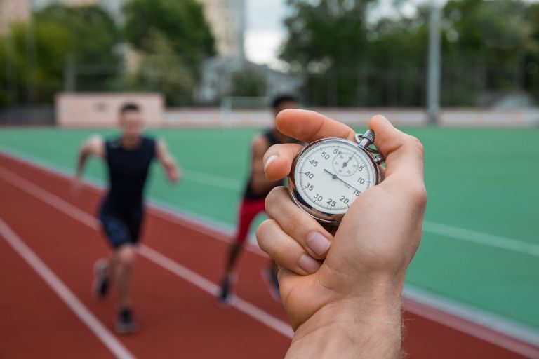 Man timing runners as they run on a track